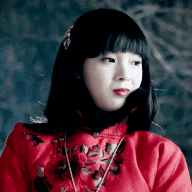 a woman is wearing a red dress with a necklace around her neck