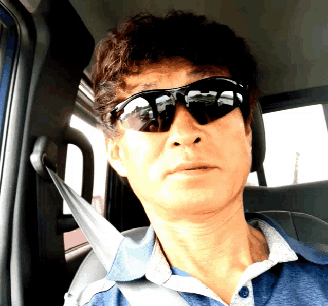 a man wearing sunglasses sits in a car