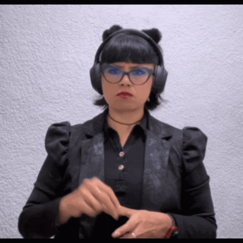 a woman wearing a black jacket and headphones is making a funny face