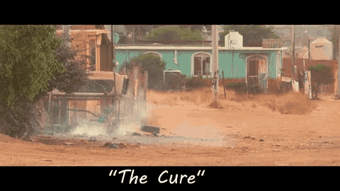 a sign that says " the cure " in the middle of a dirt field