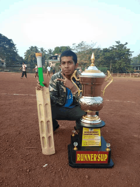 a young man kneeling next to a trophy that says runner 's up on it