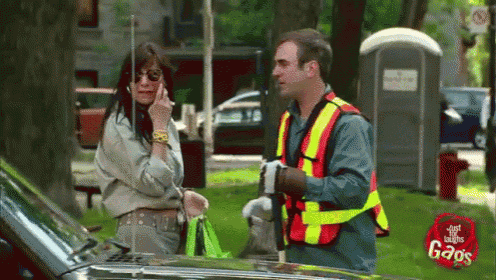 a woman talking on a cell phone next to a man wearing a safety vest