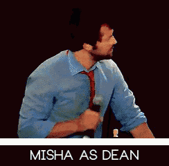 a man in a blue shirt and tie is holding a microphone and says misha as dean on the bottom