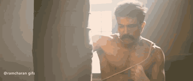 a man without a shirt is hitting a punching bag in a gym .