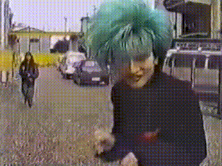 a woman with green hair is walking down the street