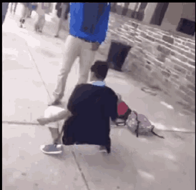 a man in a blue jacket is standing next to a man kneeling down