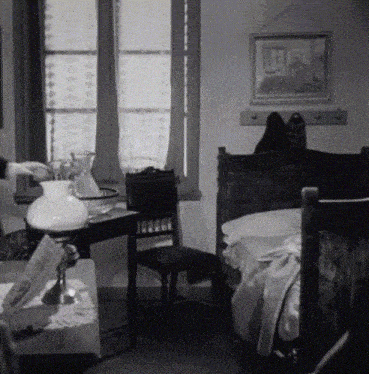 a black and white photo of a bedroom with a painting on the wall above the bed