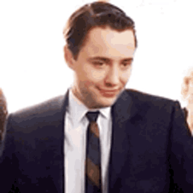 the man is wearing a suit and tie and smiling .