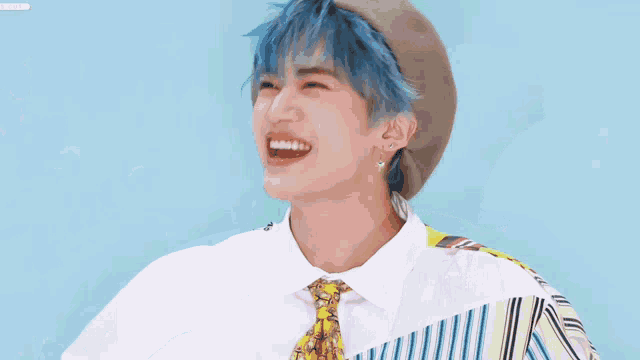 a young man with blue hair is wearing a hat and tie and laughing