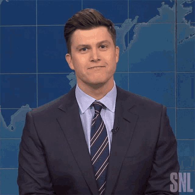 a man in a suit and tie with the snl logo on his chest