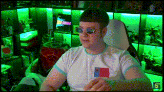 a man wearing sunglasses and a white shirt is sitting in a chair in a room with green lights .