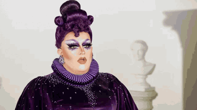 a drag queen in a purple dress with a bbc three logo on the bottom