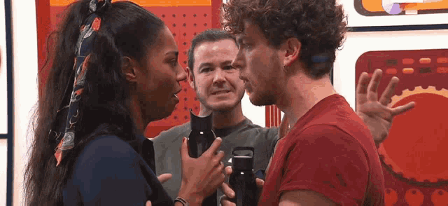 a man and a woman are talking to each other in front of a man holding a camera .