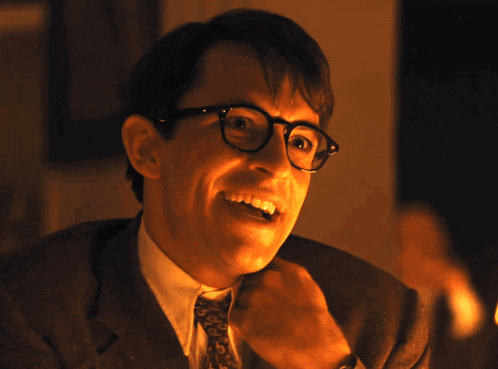 a man in a suit and tie is smiling with his hand on his chin