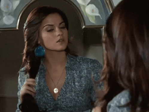 a woman brushing her hair in front of a mirror with a picture of flowers on it