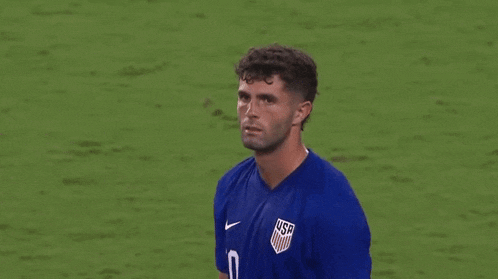 a man wearing a blue shirt is standing on a soccer field .