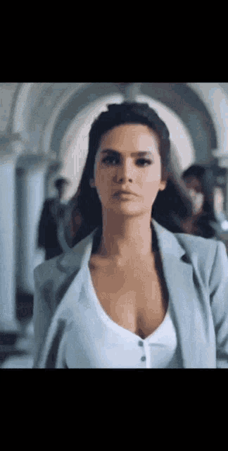 a woman in a white shirt and a grey jacket is standing in a hallway