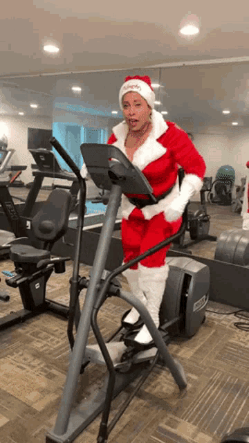 a woman in a santa suit is riding an elliptical machine