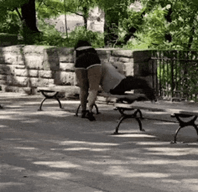 a woman is sitting on a bench in a park with her legs crossed .