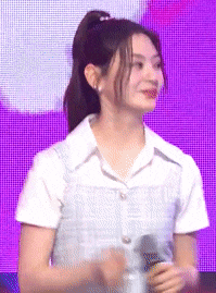 a woman wearing a white shirt and a ponytail is holding a microphone .