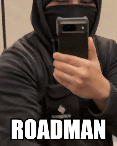 a man wearing a mask takes a picture of himself in a mirror with the word roadman written below him