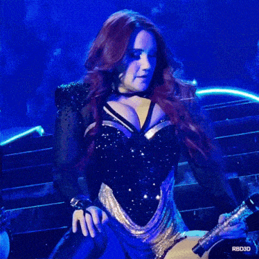 a woman with red hair is holding a microphone in front of a blue background