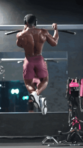 a man wearing headphones is doing a pull up on a bar in a gym