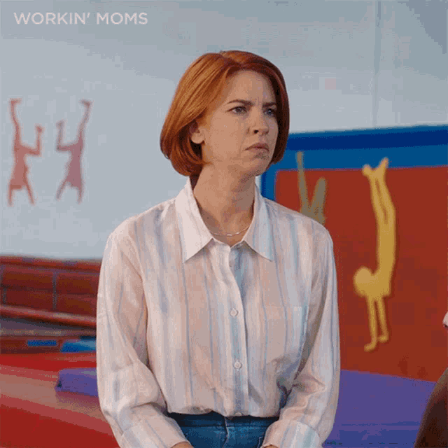 a woman in a striped shirt is sitting in front of a gym with the words workin ' moms on the bottom