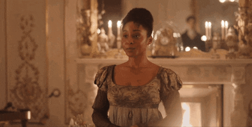 a woman stands in front of a fireplace in a room