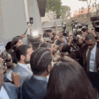 a crowd of people are gathered in front of a building including a man in a suit and tie