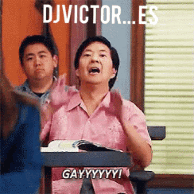 a man in a pink shirt is sitting at a desk with his hands in the air and says " dj victor es "