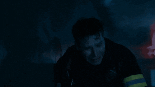 a man is crying in a dark room with a walkie talkie on his shoulder