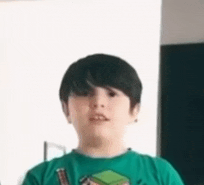 a young boy wearing a green t-shirt is standing in a room .