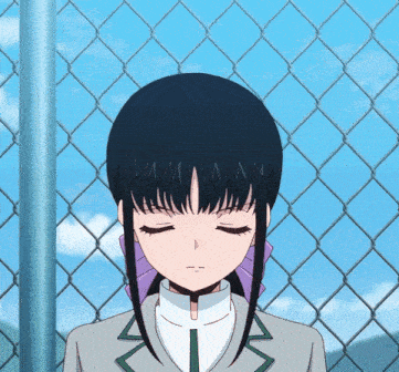 a girl stands in front of a chain link fence with her eyes closed and the letters nm on her hair