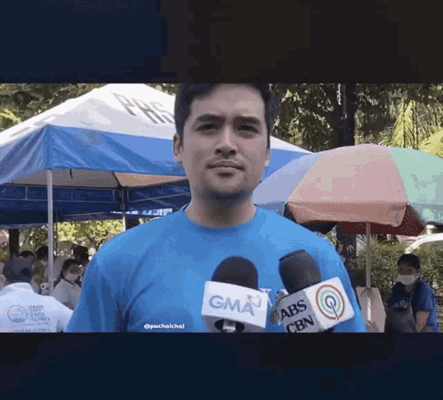 a man wearing a blue shirt with a gma logo on the front
