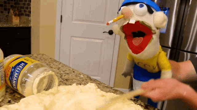 a bottle of hellman 's mayonnaise is on a counter next to a puppet
