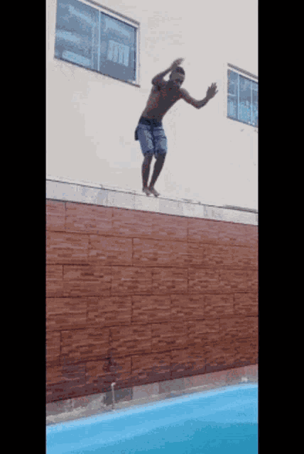 a man is jumping into a swimming pool from a ledge