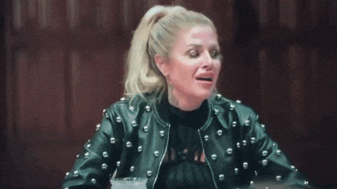 a woman wearing a black leather jacket with studs is sitting at a table with a drink .