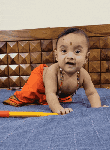 a baby is crawling on a blue blanket with a yellow stick