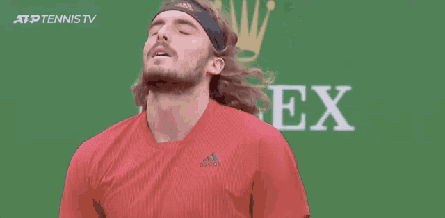 a man wearing a red adidas shirt stands in front of a green background