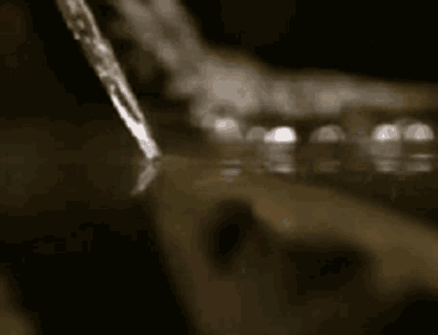 a black and white photo of a person pouring water into a cup .
