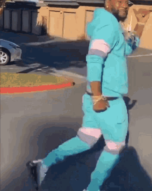 a man in a blue hoodie and blue pants is walking down the street