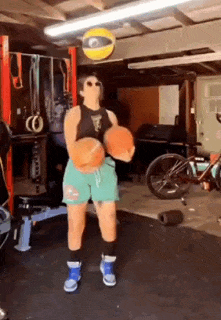 a woman is holding a basketball in a garage .