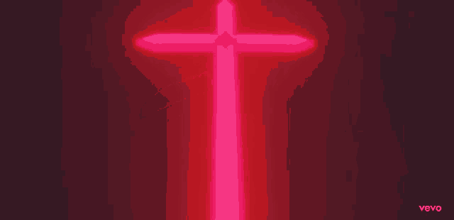 a pink neon cross is lit up on a black background