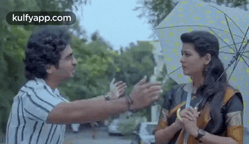 a man and a woman are standing under an umbrella in the rain and talking to each other .