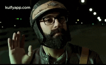 a man with a beard is wearing a helmet and glasses .