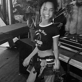 a black and white photo of a woman in a crop top dancing in front of a dj .