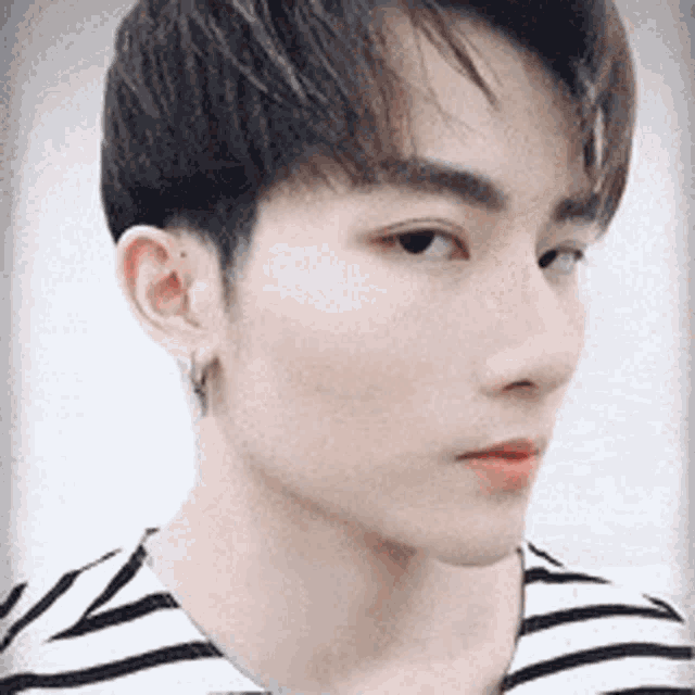 a close up of a young man 's face wearing a striped shirt .