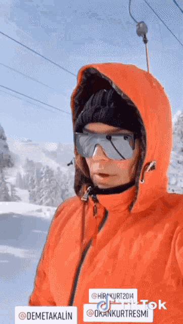 a woman wearing a red jacket and goggles has a sticker that says demetakalin on it