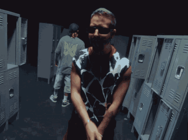 a man wearing sunglasses is standing in a hallway filled with lockers